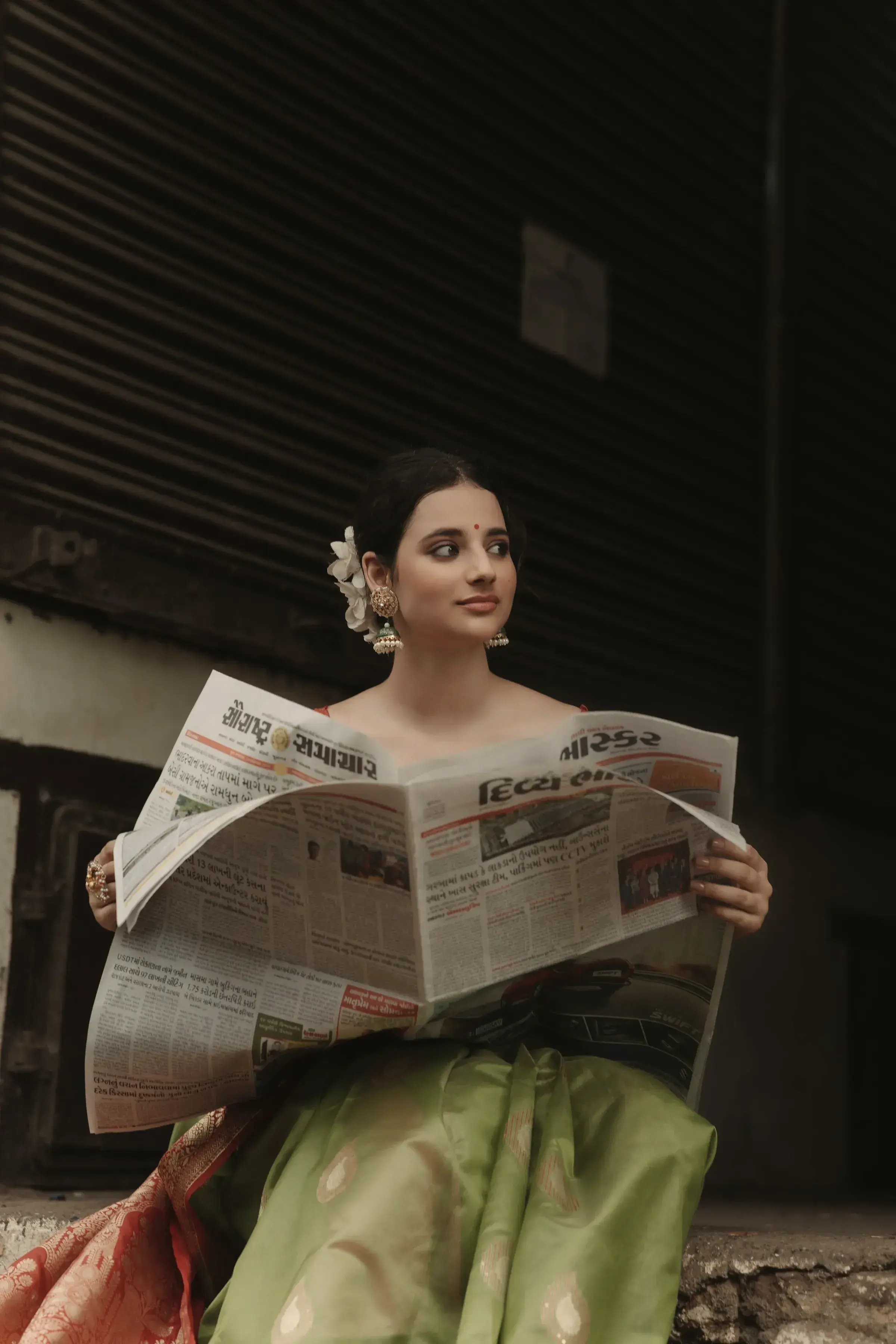 A woman in a pistachio Chanderi saree reading the morning paper on a Kolkata pavement