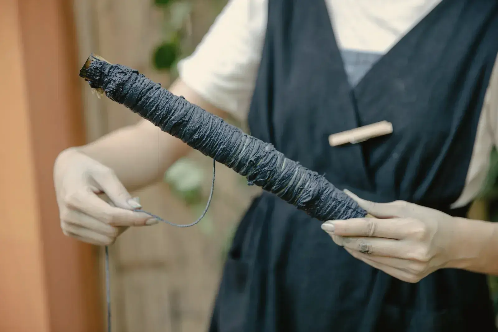Hands holding a skein of indigo dyed cotton yarn wound on a stick