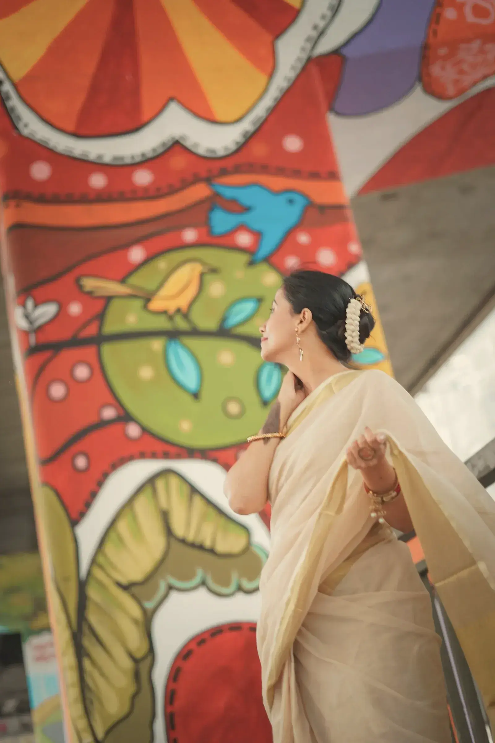 A woman in an undyed kora tussar saree in front of a painted Kolkata wall